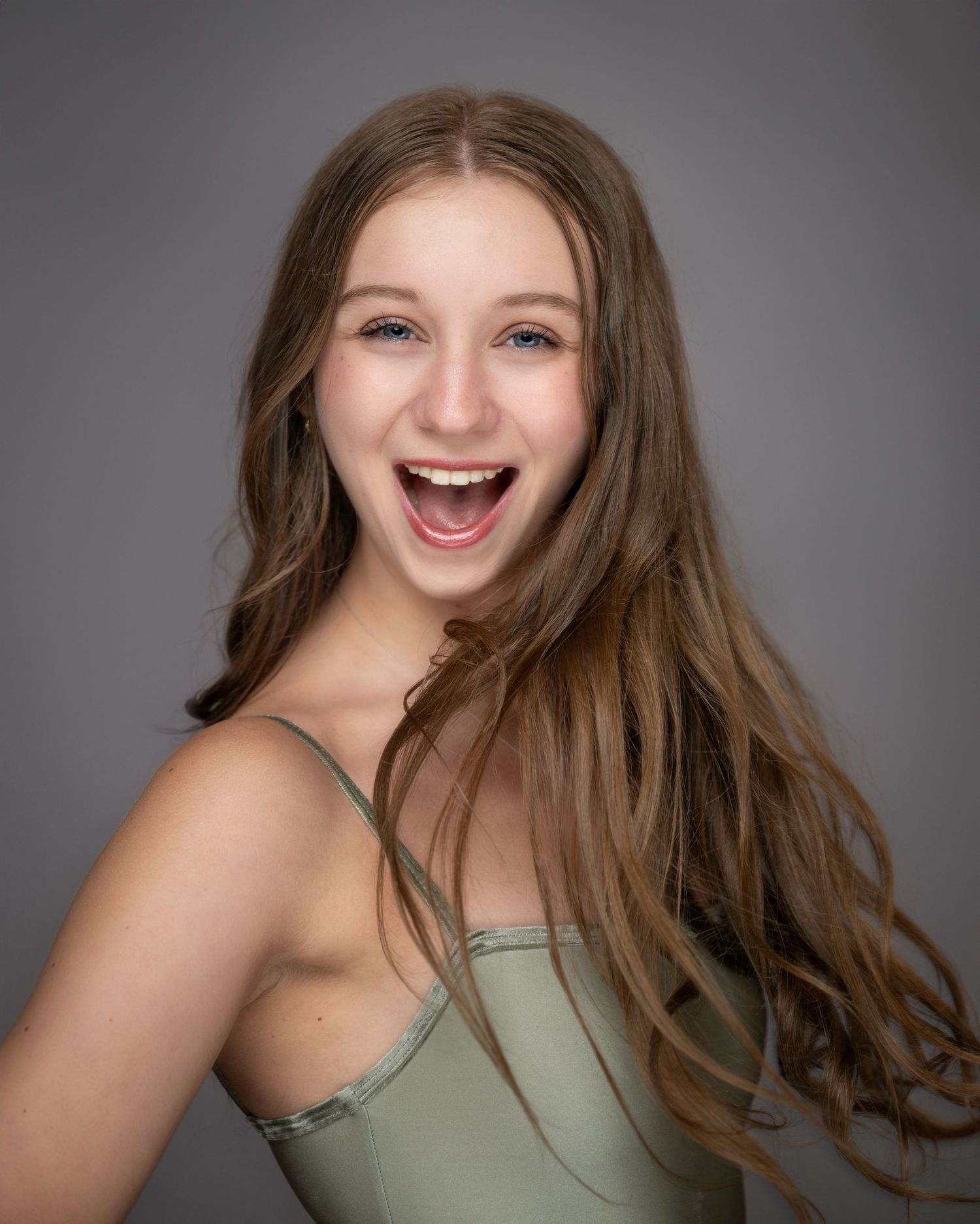 Energetic dance portrait showing joyful expression and long brown hair against gray background.
Pittsburgh Dance Photographer