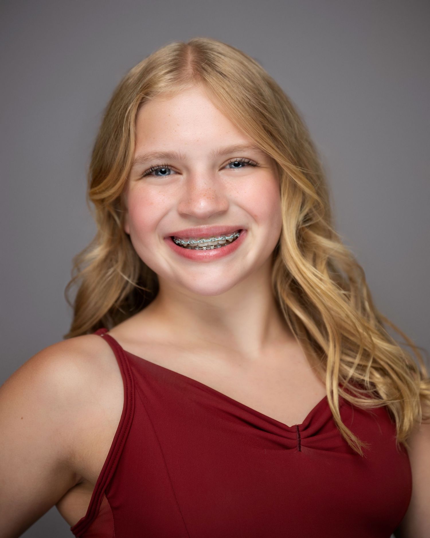 Dance portrait in burgundy top showing bright smile with braces and wavy blonde hair.
Pittsburgh Dance Photographer