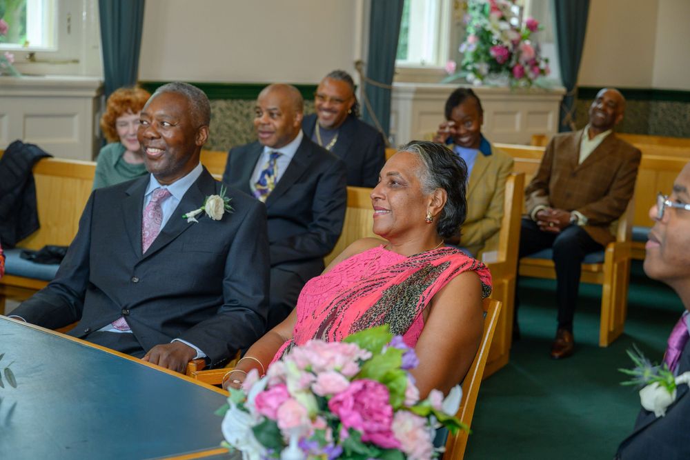 Wedding ceremony attendees sit in rows at a beautifully decorated indoor venue.