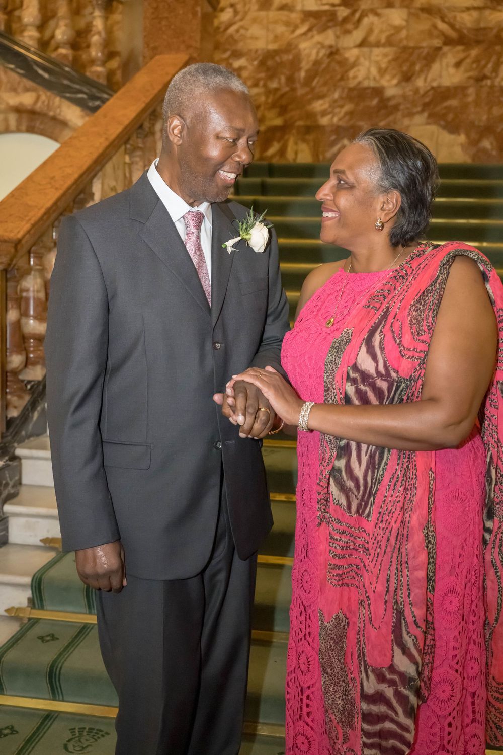 A couple in formal attire shares joyful moments in church while standing next to wooden pews.