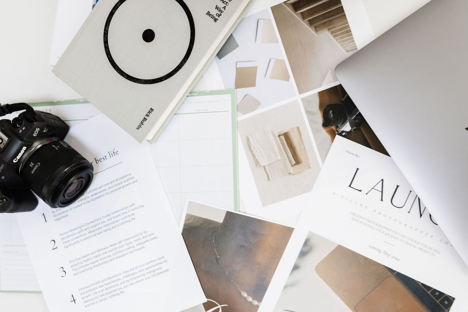 Flatlay of branding materials and photography equipment on white surface.