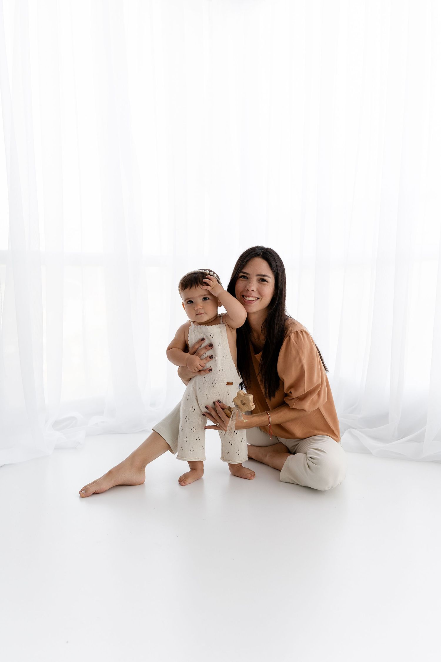 Sweet bonding moment captured against white backdrop in minimalist setting.