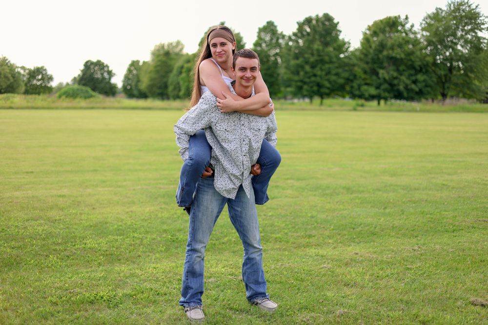 A piggyback ride moment captured in an open green field on a sunny day.