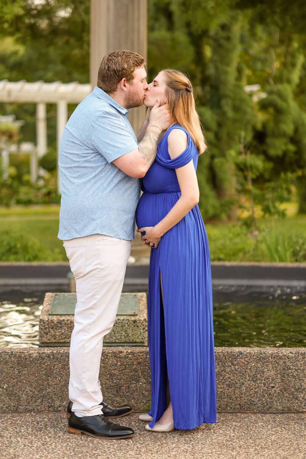 Couple shares romantic moment by fountain in garden setting at sunset.