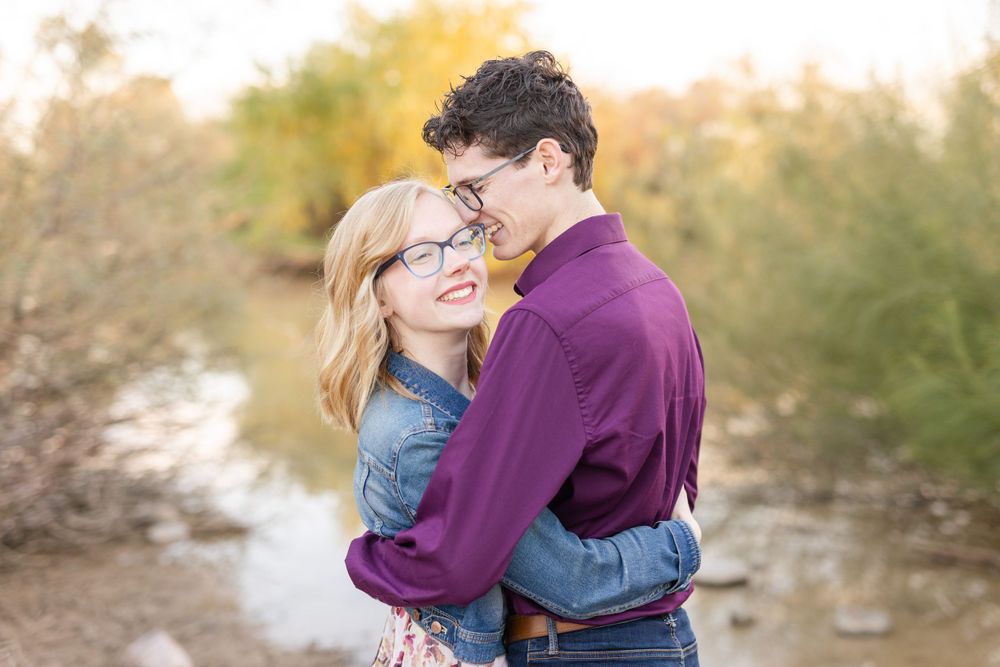 Intimate moment captured between couple against blurred natural background during sunset.
