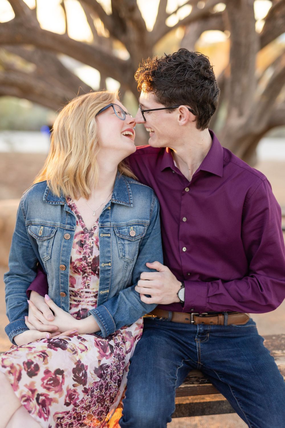Couple shares joyful moment while sitting on wooden bench in desert park setting.