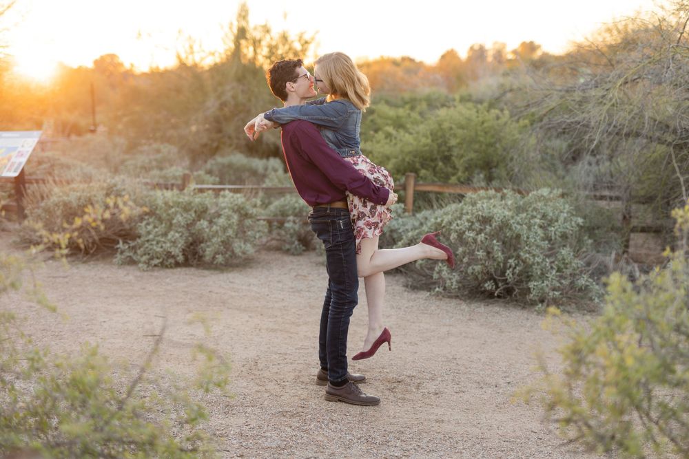 Romantic lift pose captured during sunset photoshoot in desert landscape.