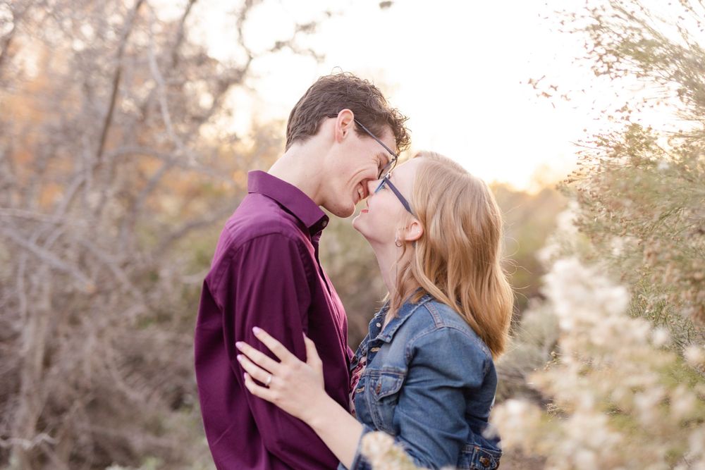 Tender moment between couple against blurred desert landscape at golden hour.
