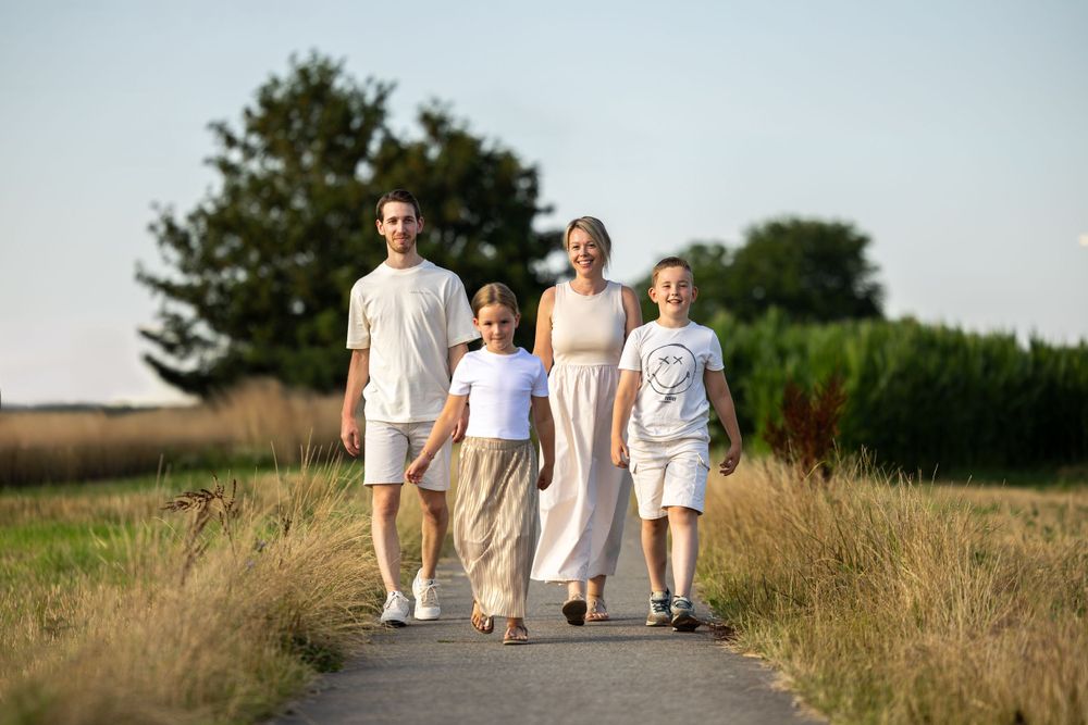 Family of four taking a stroll together on rural path in summertime.