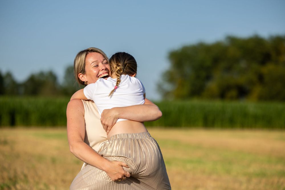 Intimate moment between mother and child in golden sunlit field.