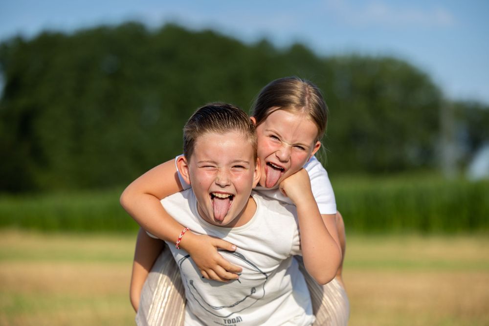 Playful piggyback moment captured in sunny outdoor field.