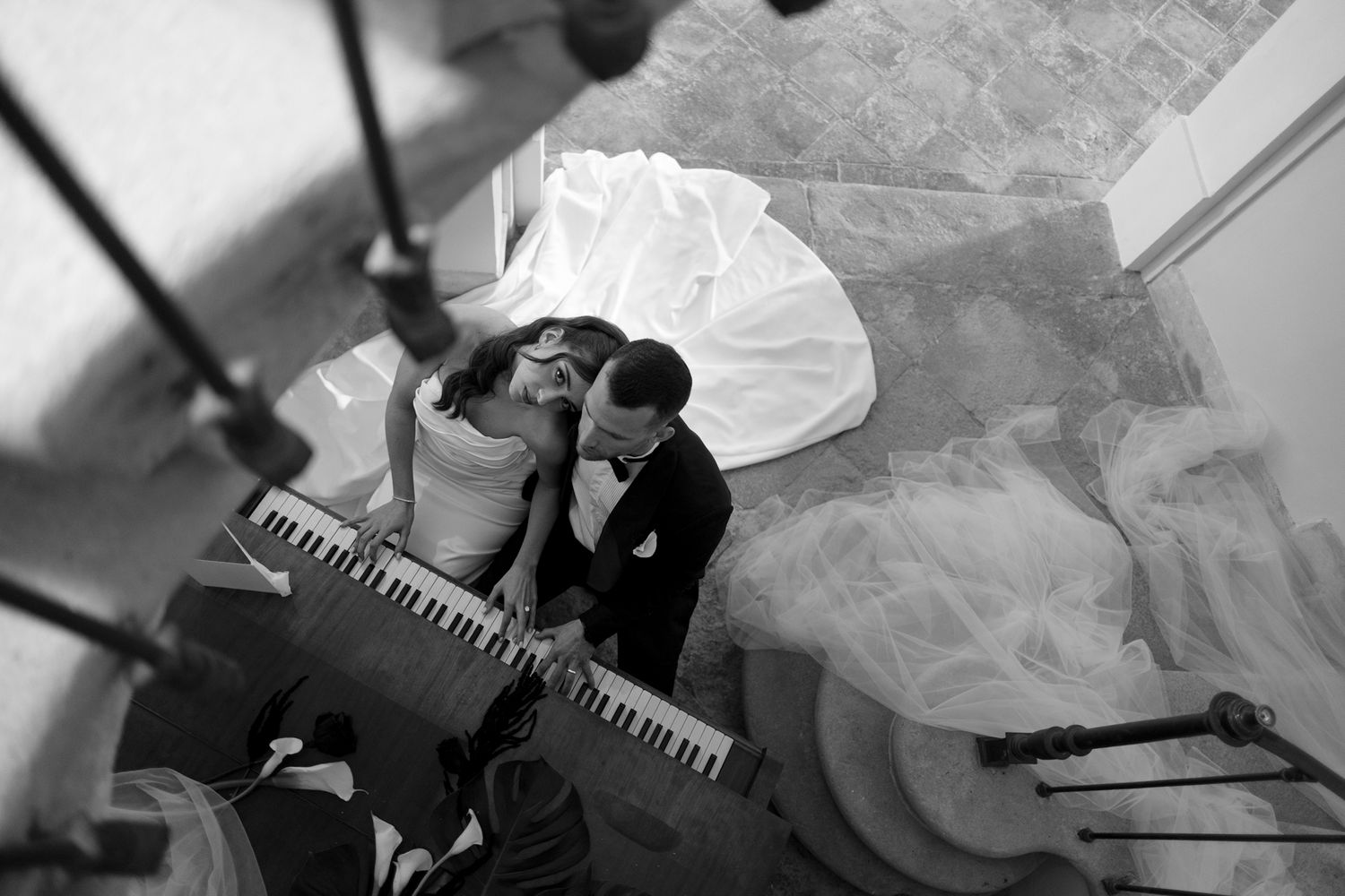 A black and white photo of groomsmen celebrating at a wedding reception in a room with wooden floors.