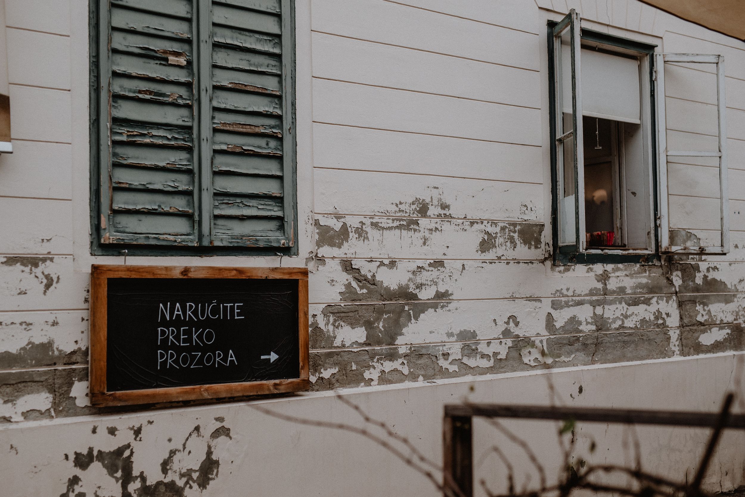Exterior of a cozy cafe in old town with a sign on the window that reads 'You Can Order From Here,' inviting customers.