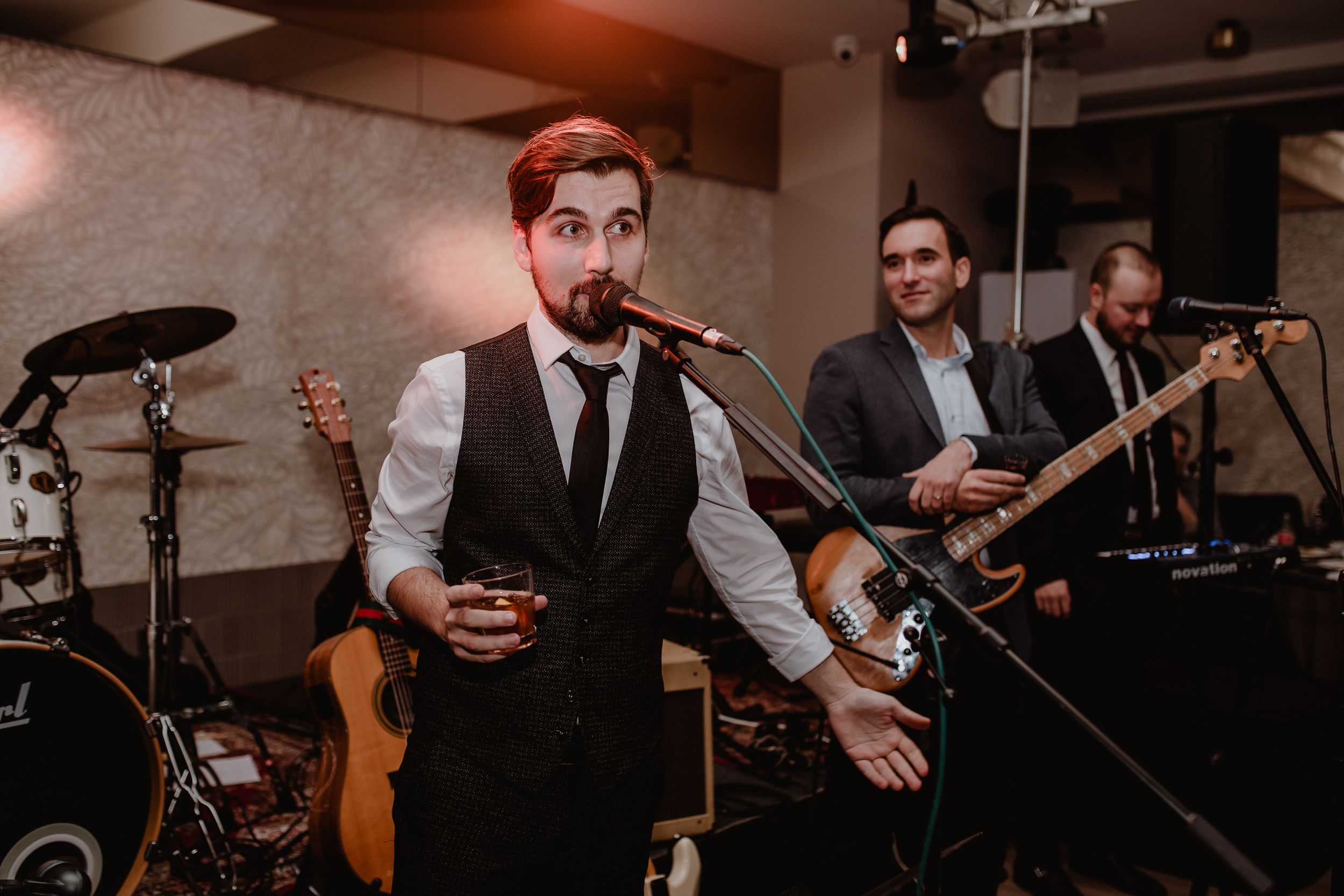Black and white photo of the best man singing a vocal performance while the groom plays guitar during the wedding party.