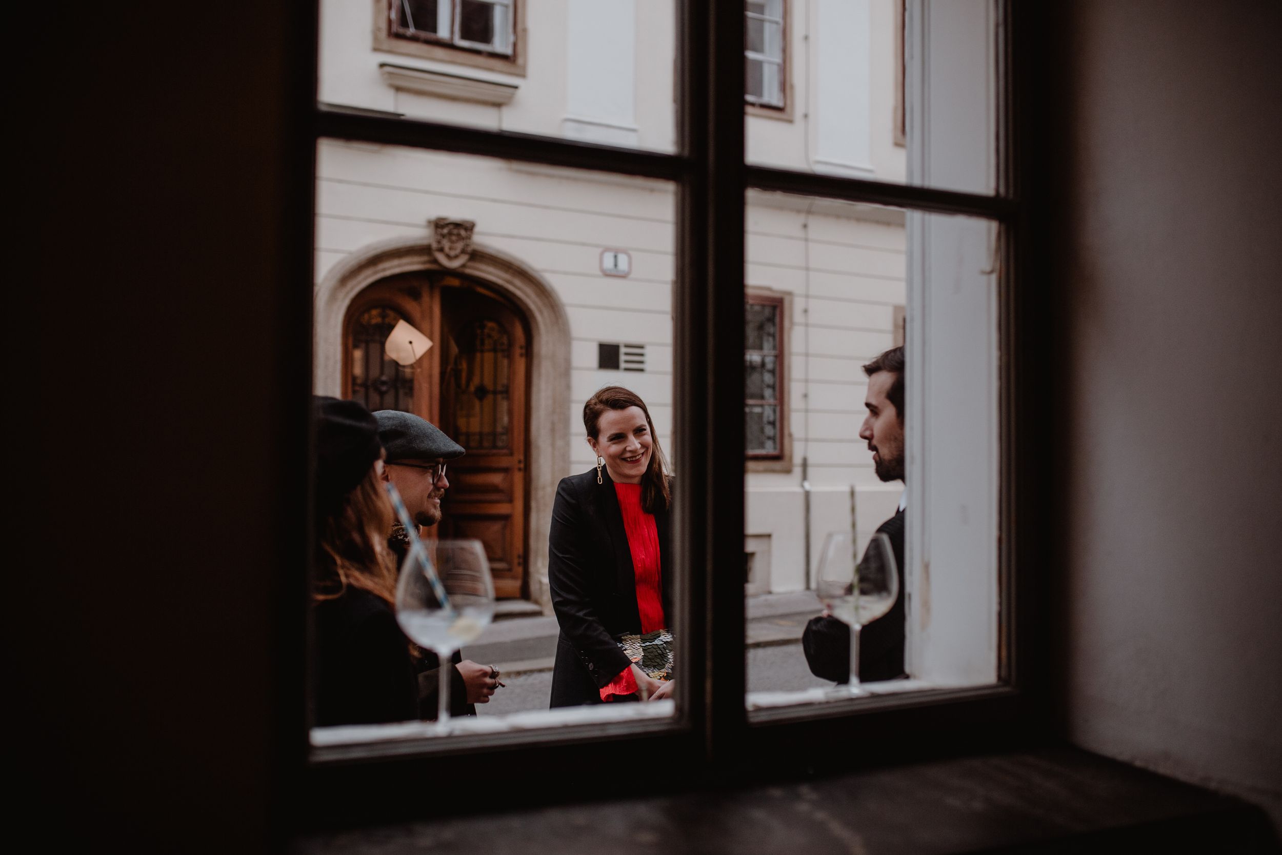 Group of wedding guests outside a quaint Upper Town cafe in Zagreb, laughing together before the wedding ceremony.