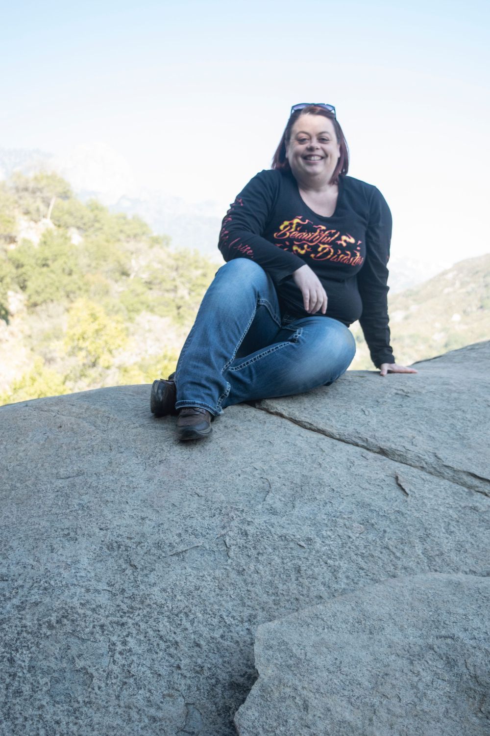 Hiker relaxing on rocky outcrop during scenic mountain trail adventure.