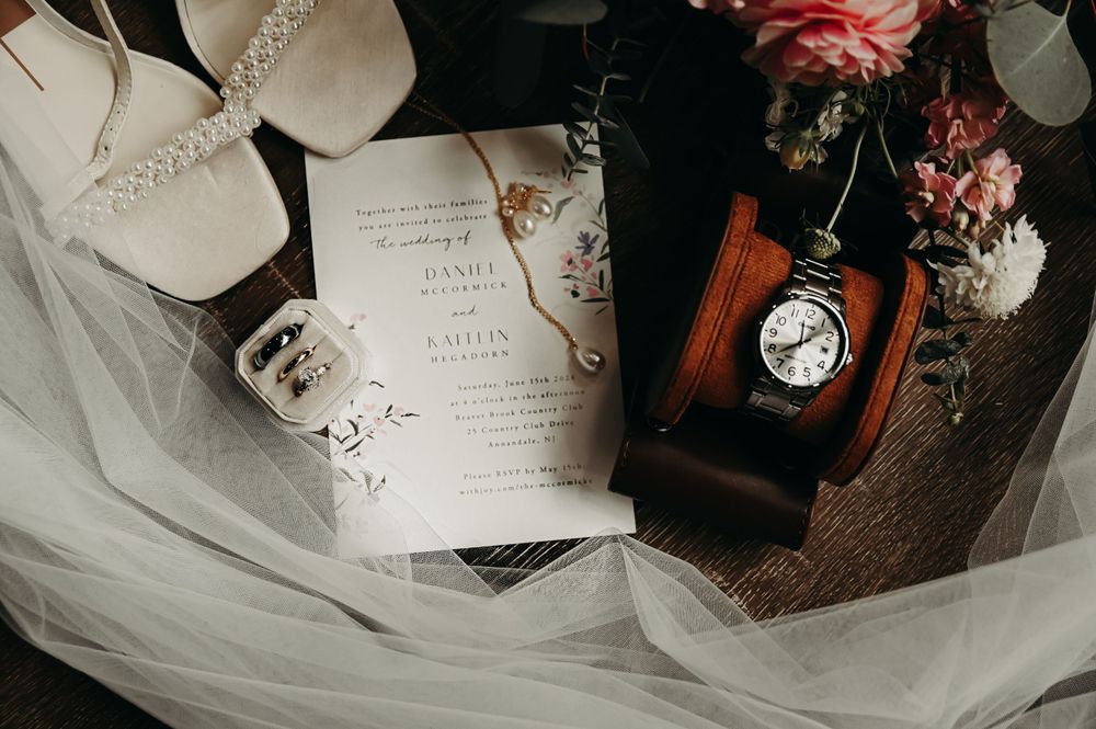 Wedding invitation and rings displayed with pink florals and vintage decor elements.