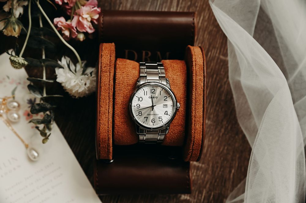 Vintage pocket watch and wedding details arranged artistically with soft lighting.