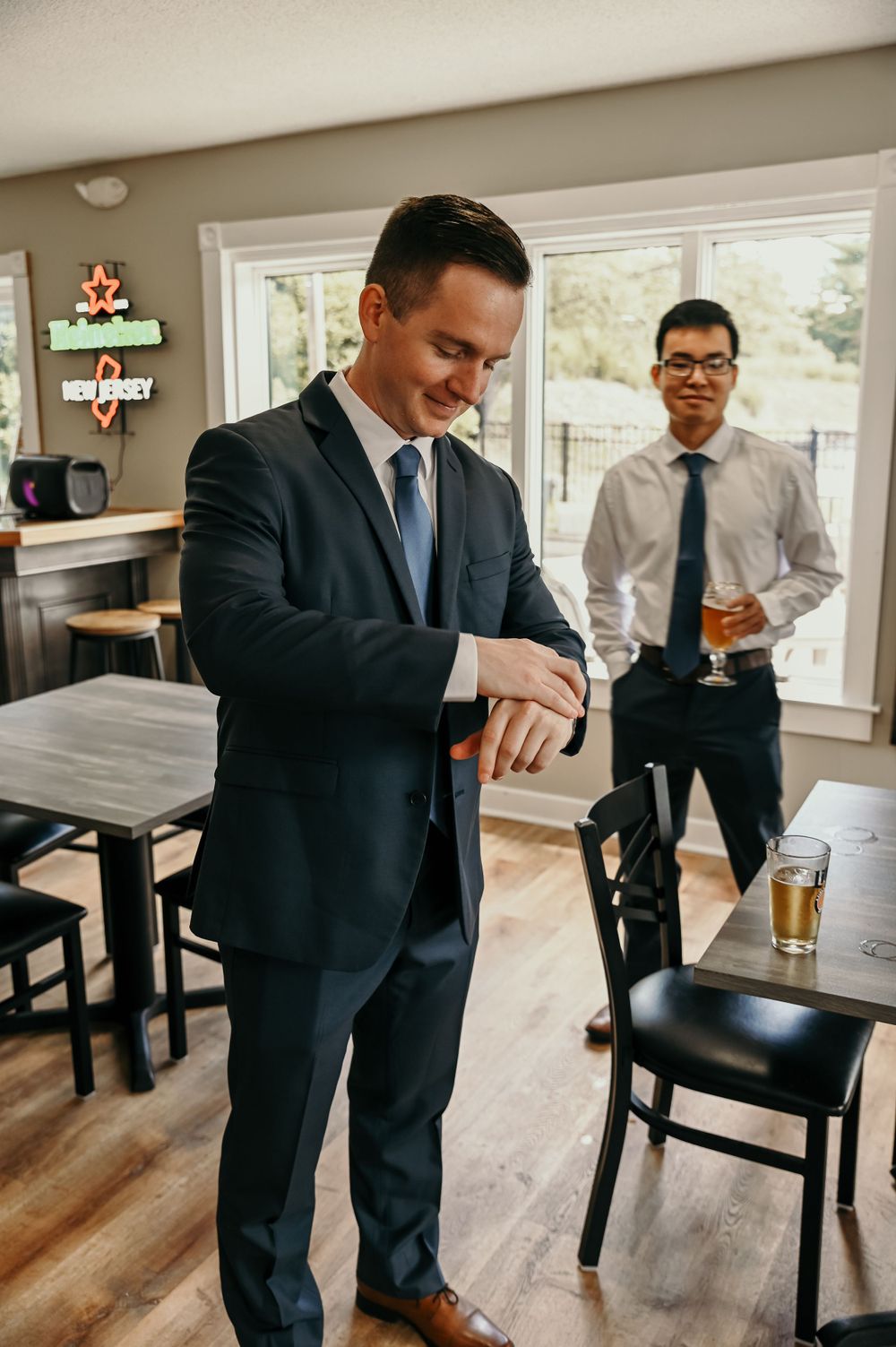 Groomsmen in dark suits socializing and having drinks before the ceremony.