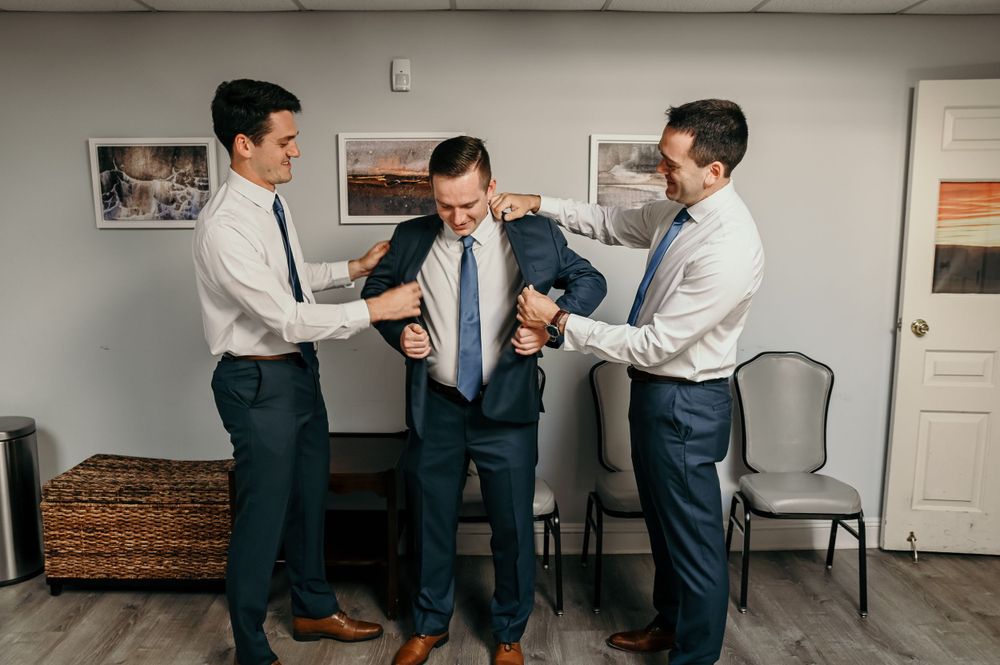 Groomsmen in matching navy suits prepare for a wedding ceremony.