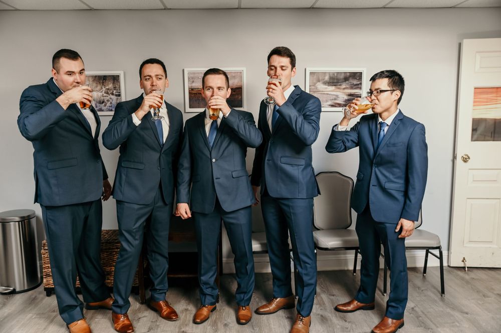 Wedding party members in coordinated navy suits pose for candid group photos.