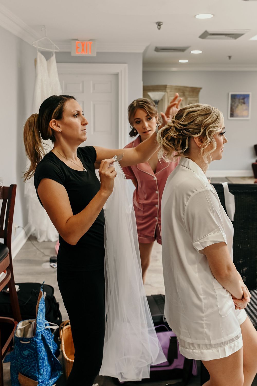 Wedding party members getting ready in a bright indoor space.