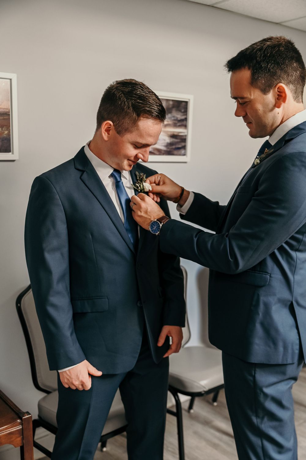 Final adjustments being made to formal attire in a bright room.