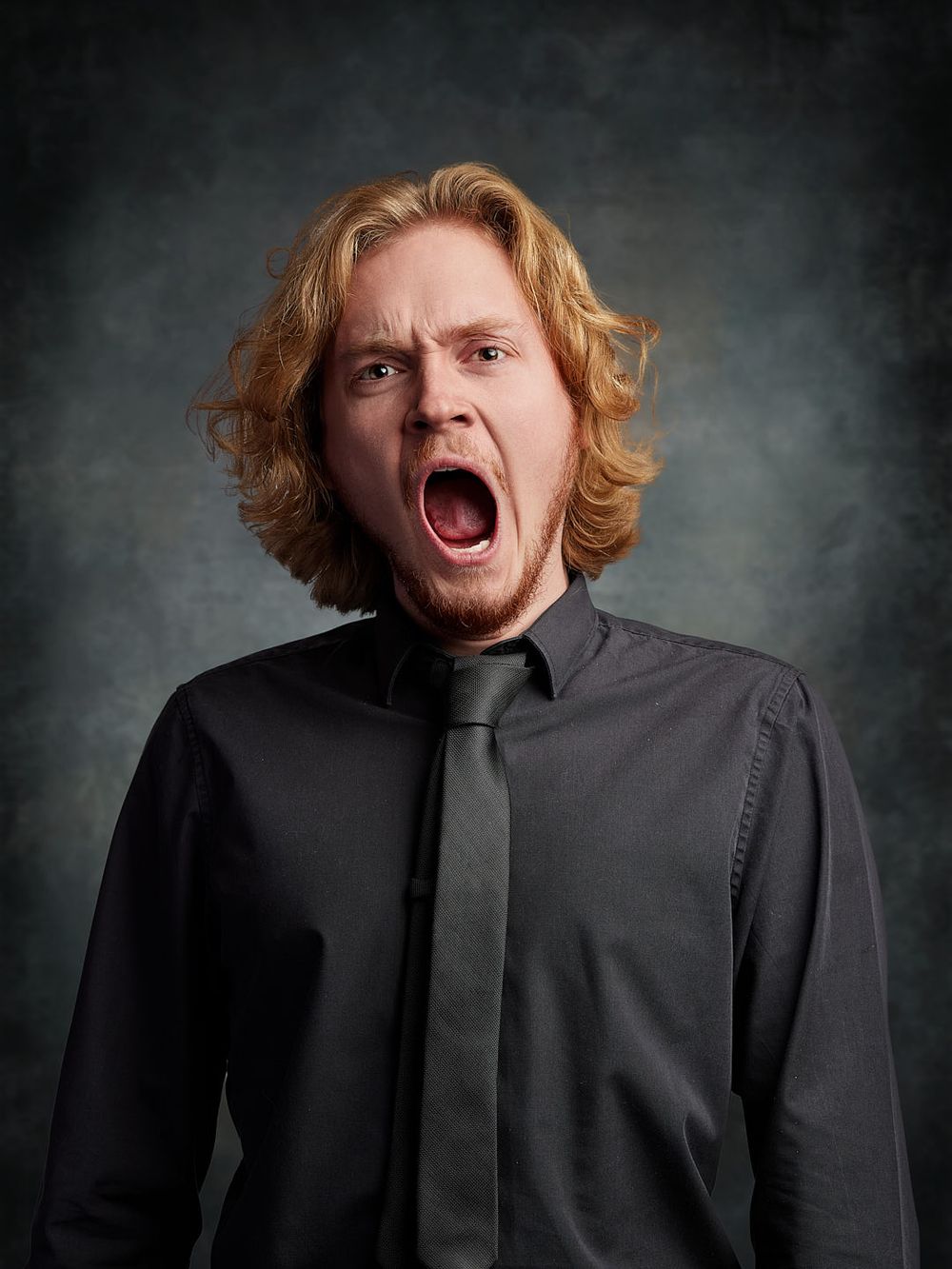A headshot of actor Ethan Leith yawning