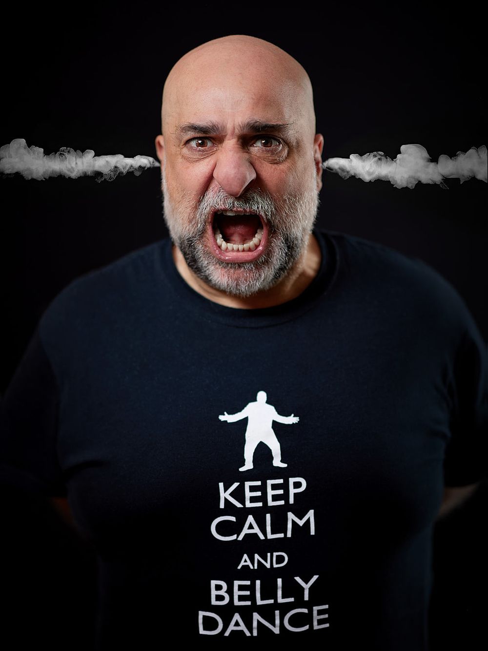 Comedian Omid Djalili with steam coming from his ears, wearing a tshirt that says "Keep Calm and Belly Dance"