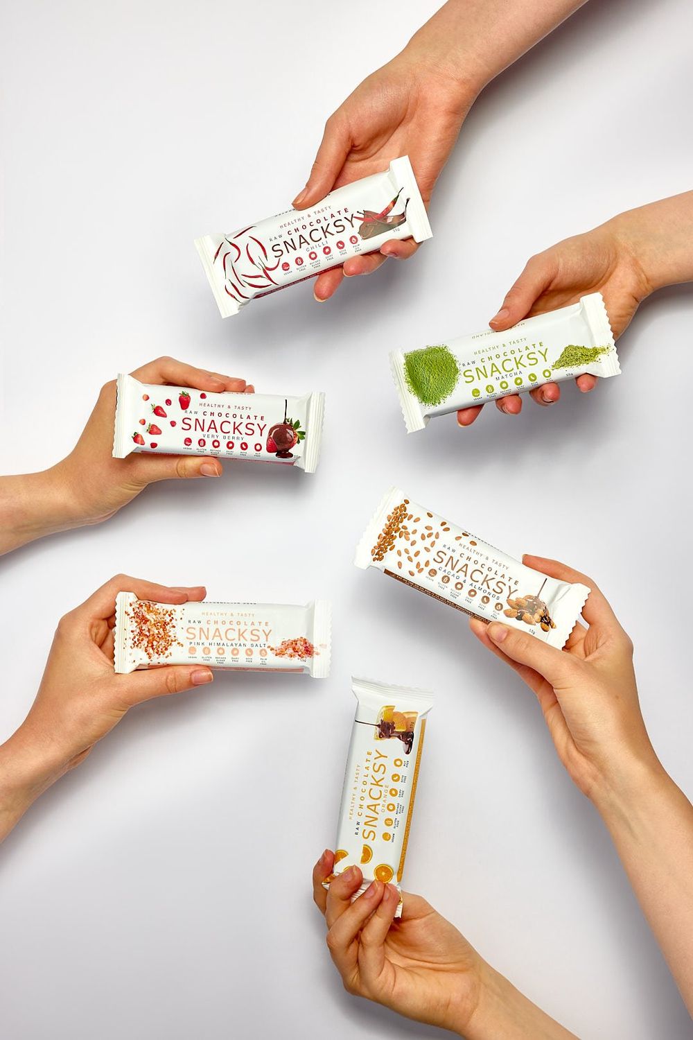 A group of hands holding Snacksy bars
