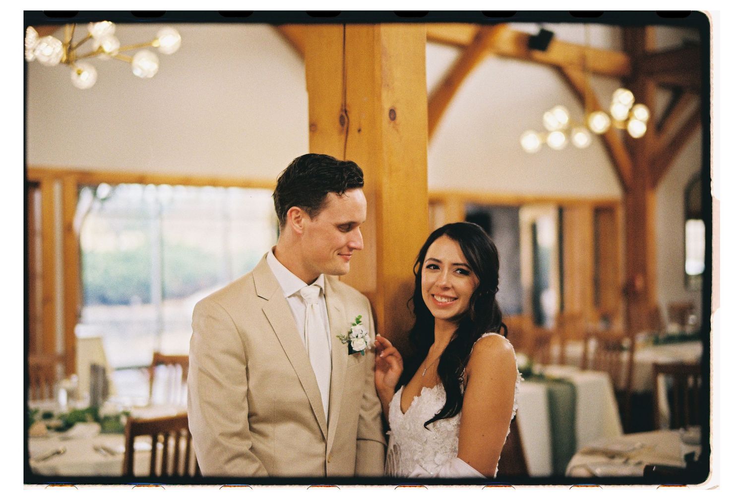 A couple shares a sweet moment together at their elegant timber-framed wedding reception venue with warm lighting.
