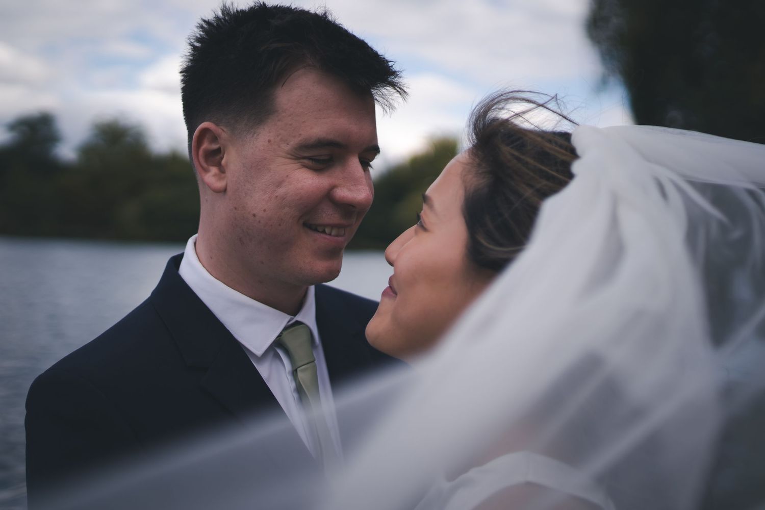 A close-up romantic moment between newlyweds with bride's veil in focus.