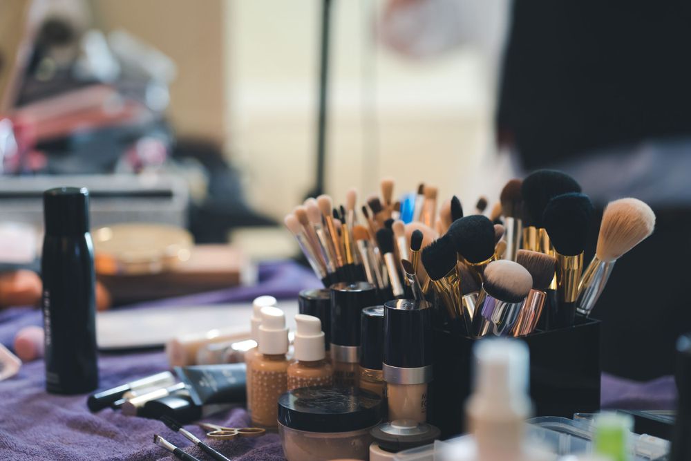 Professional makeup brushes and cosmetics arranged on purple table.