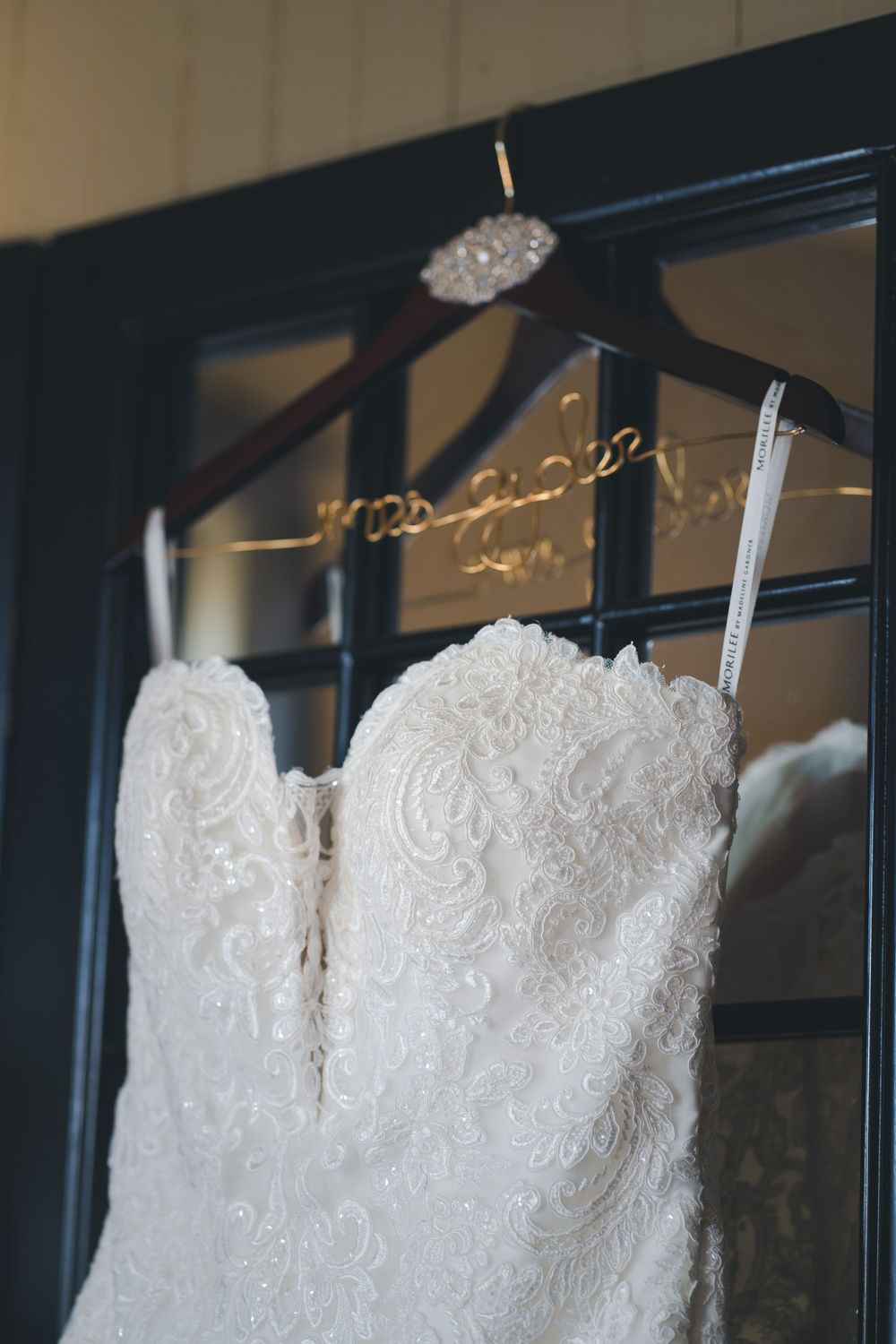 Elegant white lace wedding dress with sweetheart neckline hanging on display.
