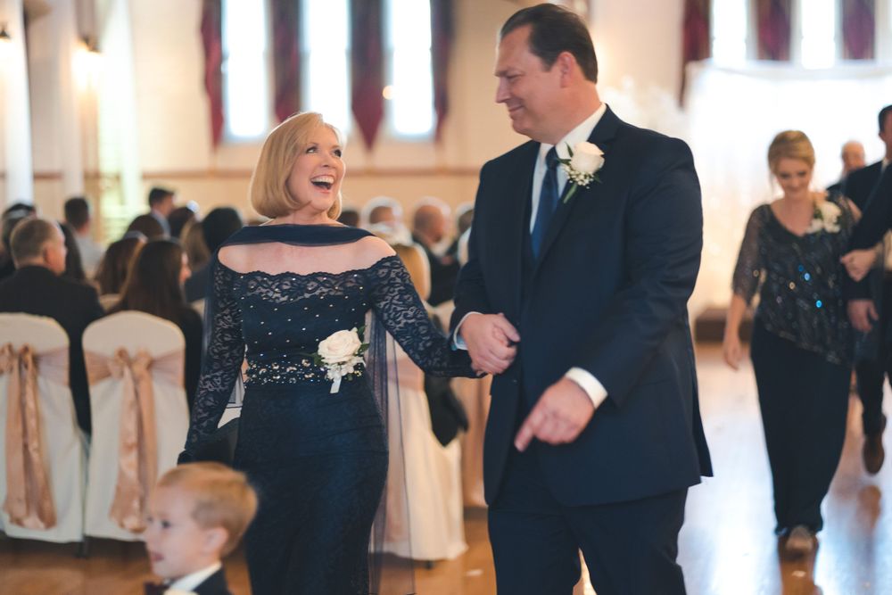 Wedding guests share a laugh while walking through an elegant reception hall.