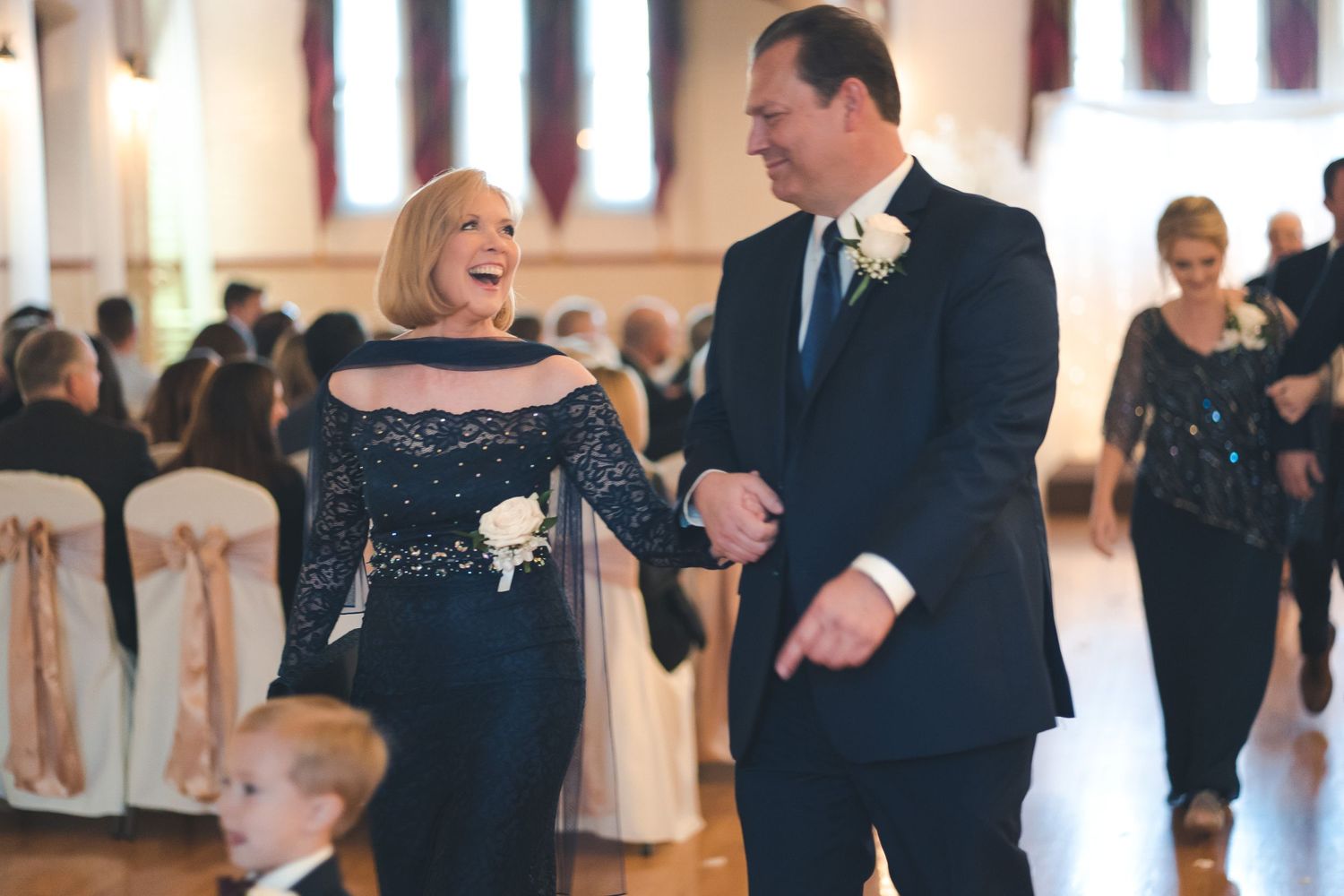 Wedding guests share a laugh while walking through an elegant reception hall.