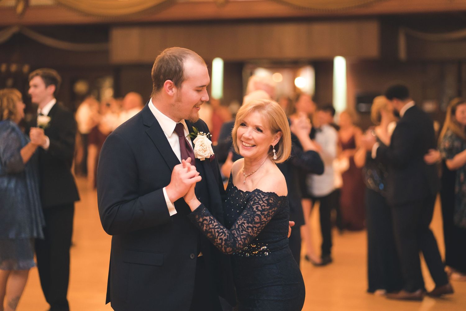 Guests dancing and celebrating at an indoor wedding reception with warm lighting.