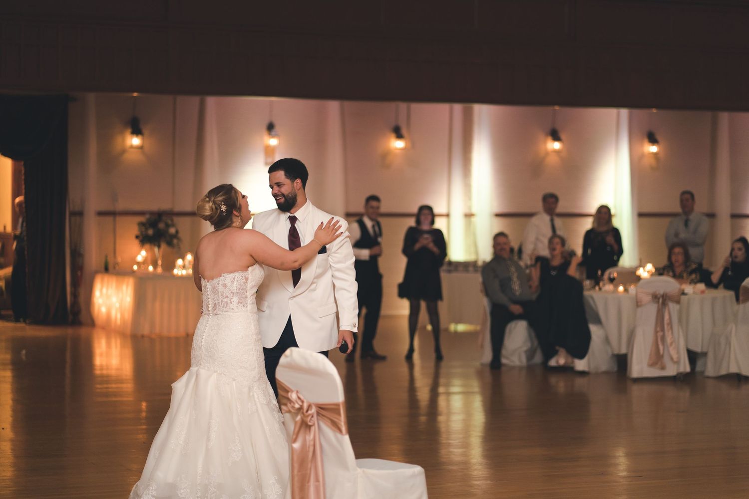 A couple shares their first dance at their wedding reception in an elegant ballroom.