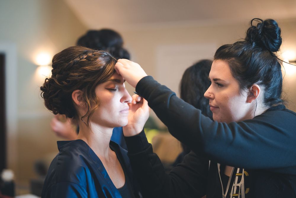 Makeup artist applying cosmetics to model during wedding preparation.