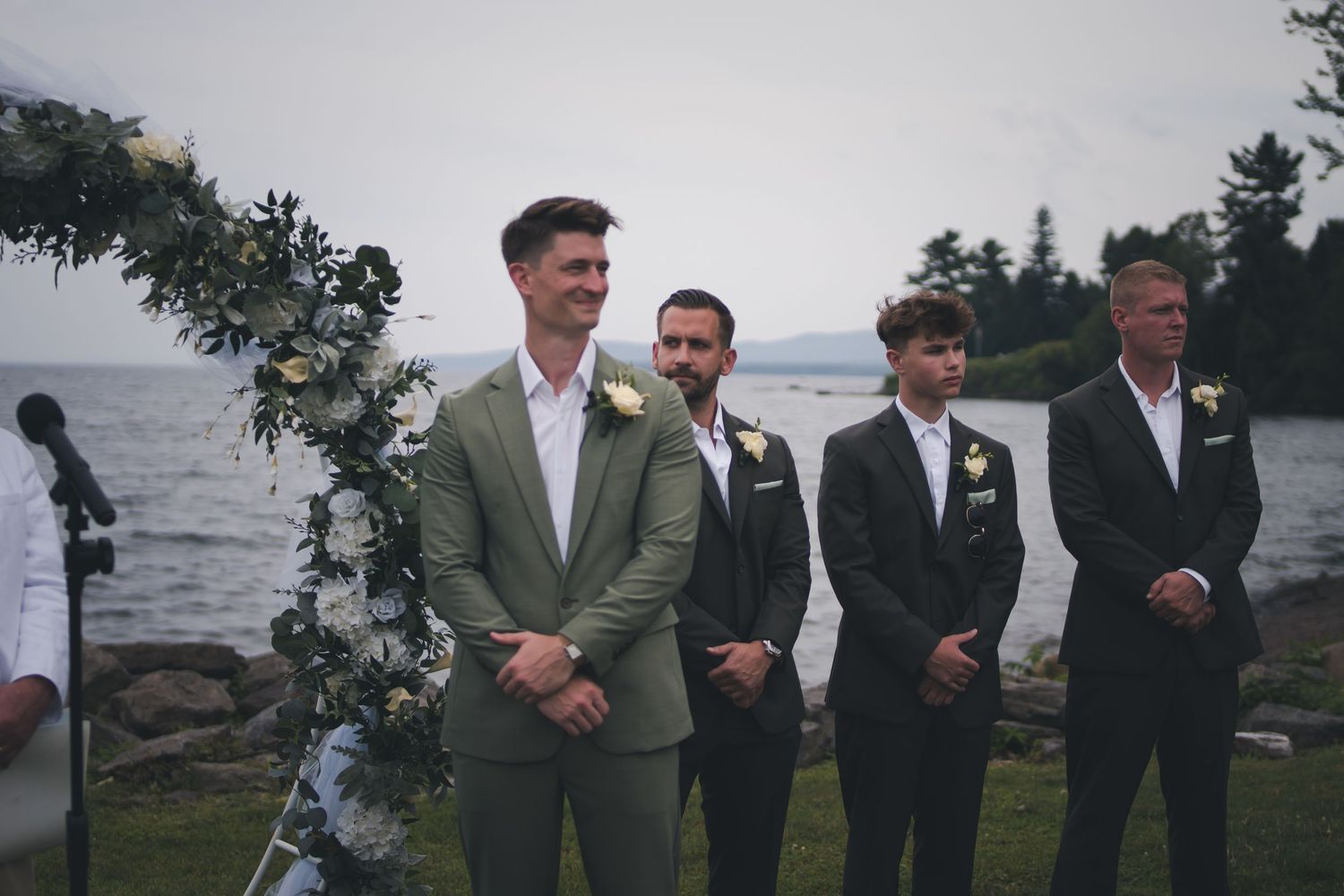 Wedding ceremony at waterfront location with participants in formal attire.