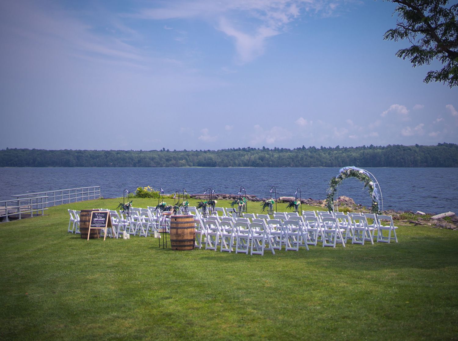 Outdoor wedding ceremony setup with white chairs and an arch overlooking a scenic waterfront.