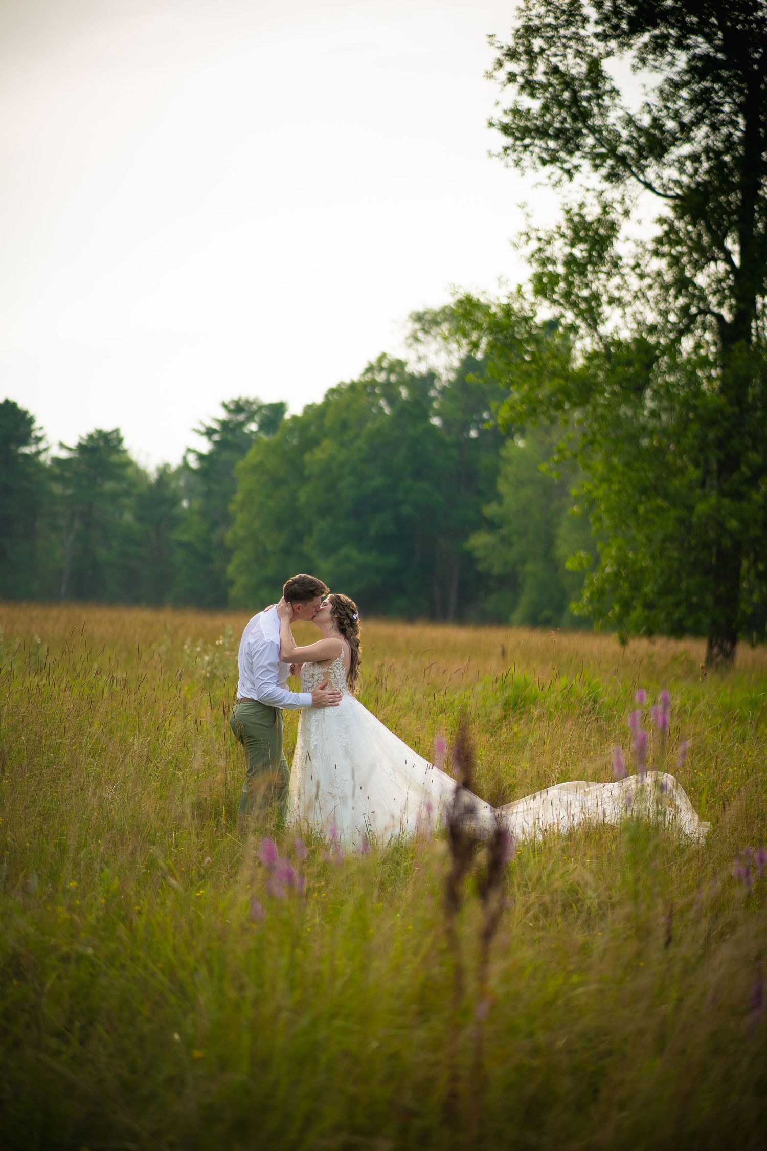 Romantic wedding portrait in tall grass meadow with soft focus.