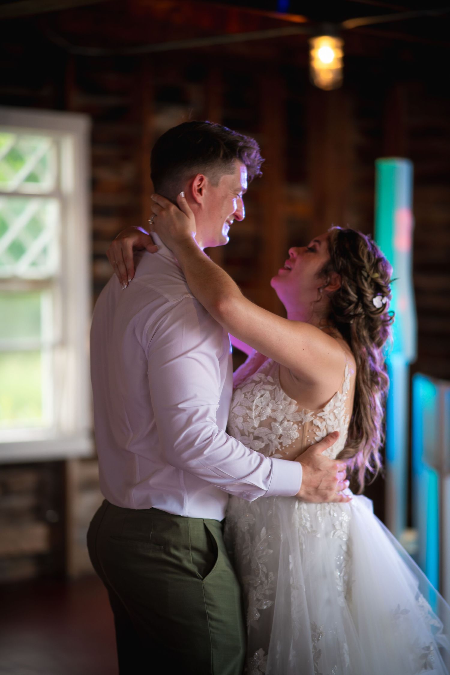 Couple shares intimate dance moment in rustic wooden venue with natural lighting.