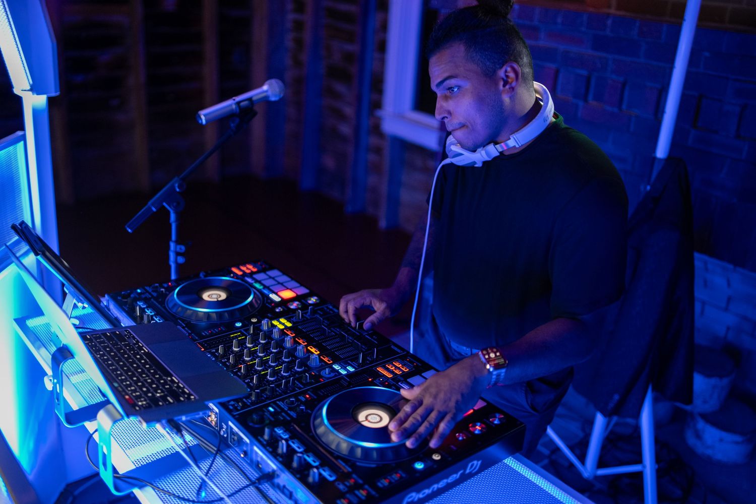 DJ performs at wedding reception with blue lighting and professional equipment.