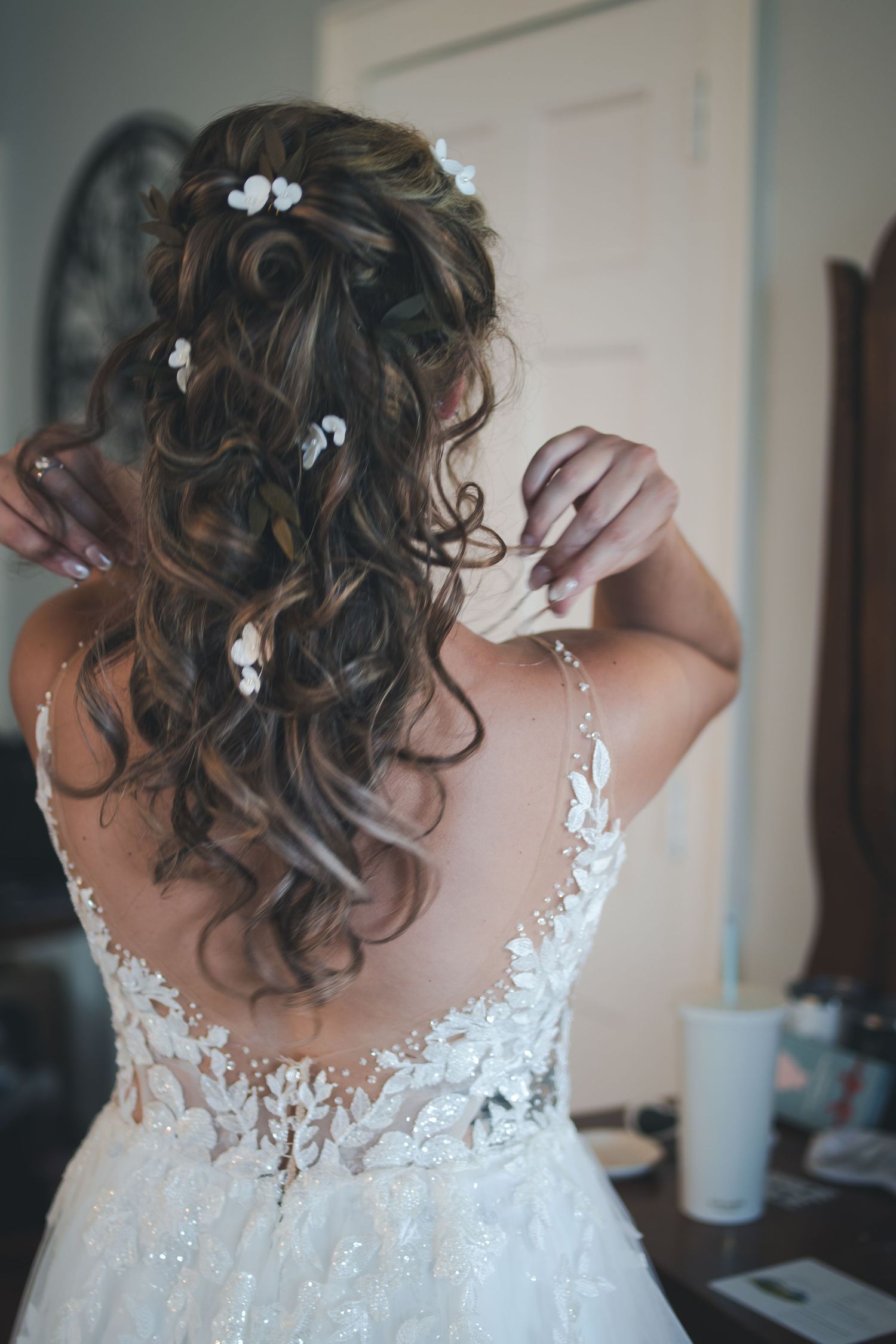Elegant bridal hairstyle with curls and small white floral accessories.