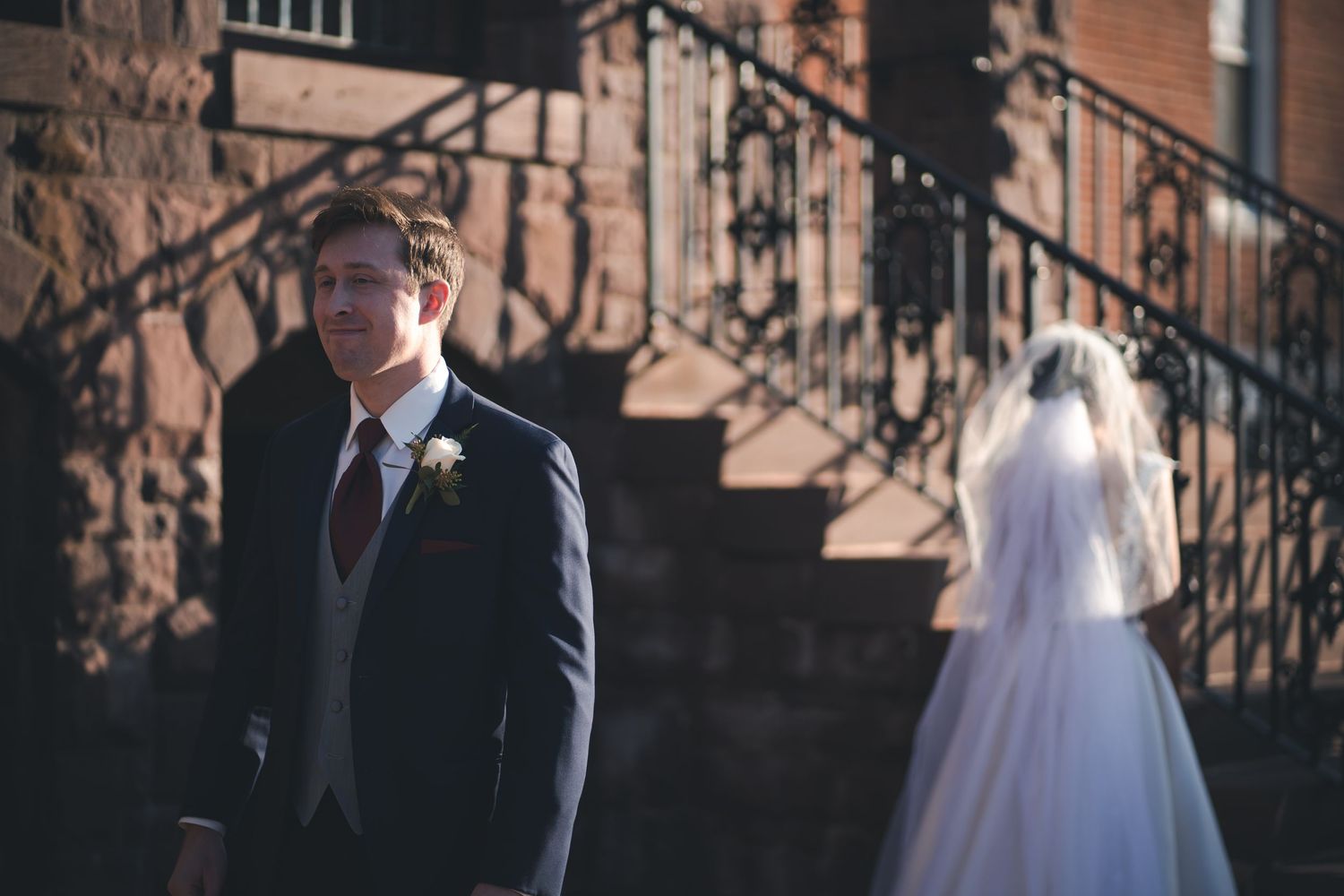 A wedding scene against stone architecture with elegant stairs and iron railings.