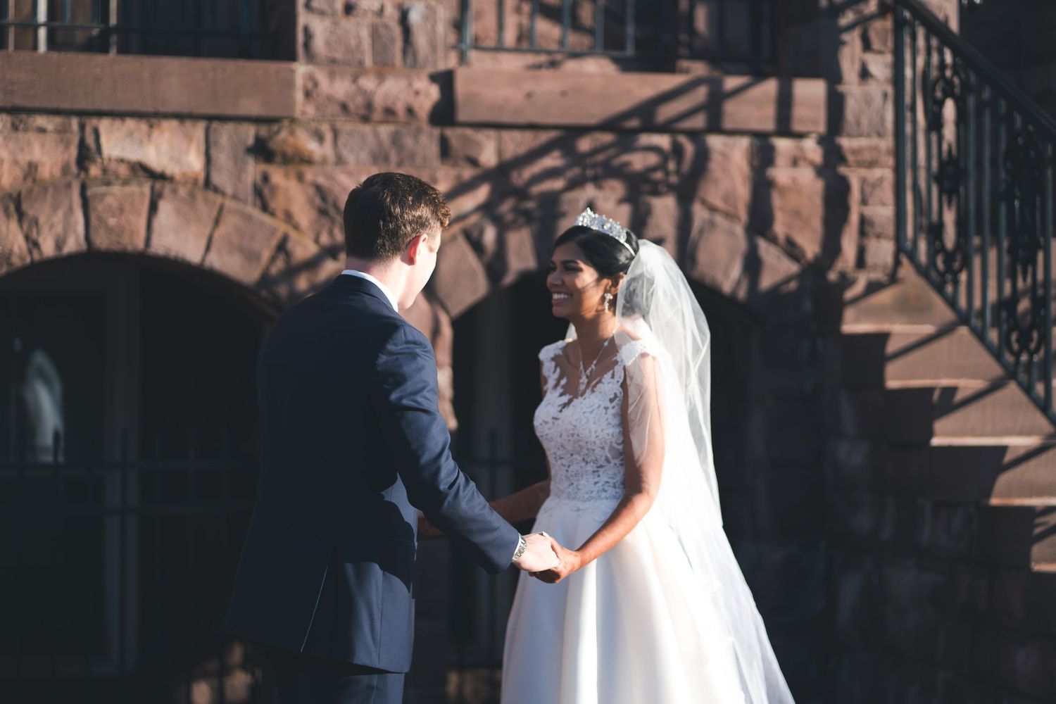 A tender wedding moment captured against rustic stone architecture.