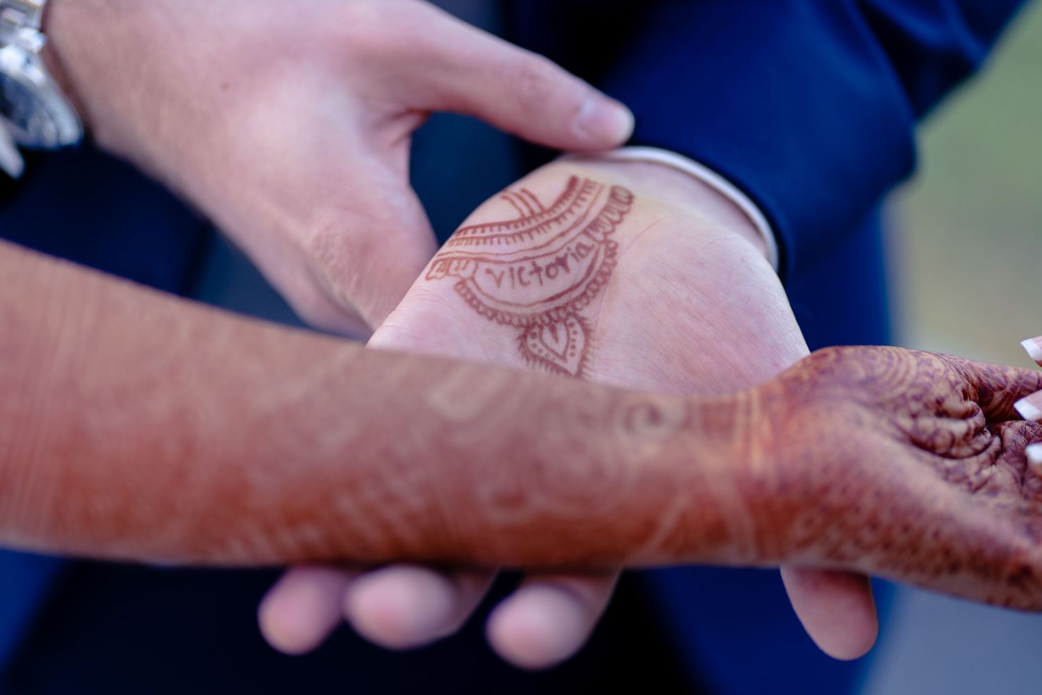 Close-up detail of intricate henna design on hands during a wedding ceremony.