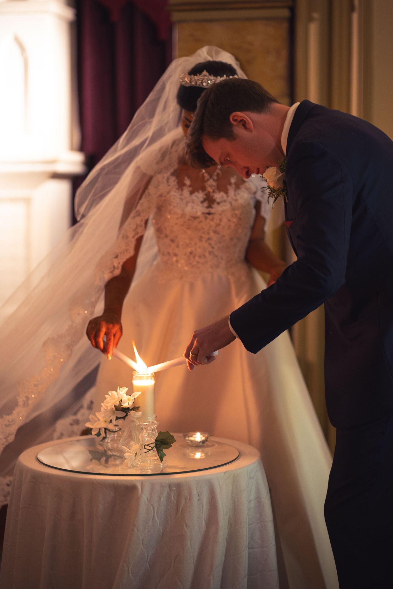 Newlyweds lighting unity candles together during their wedding ceremony.