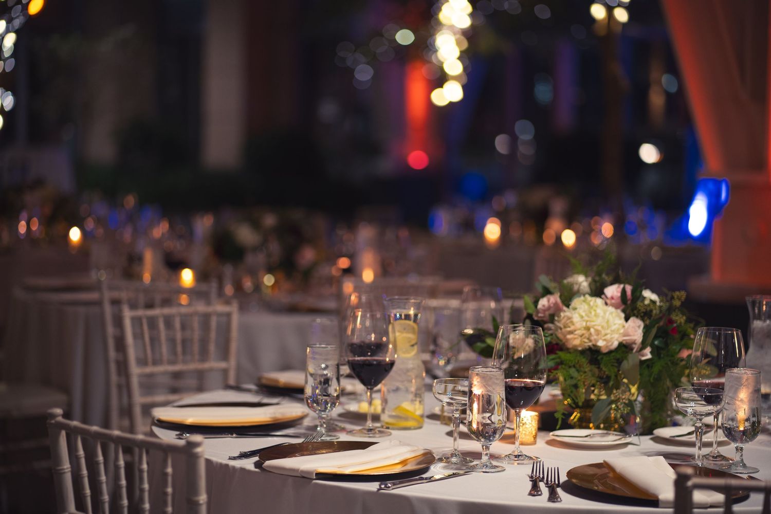 An elegant wedding reception table setting with floral centerpieces and glowing candlelight.